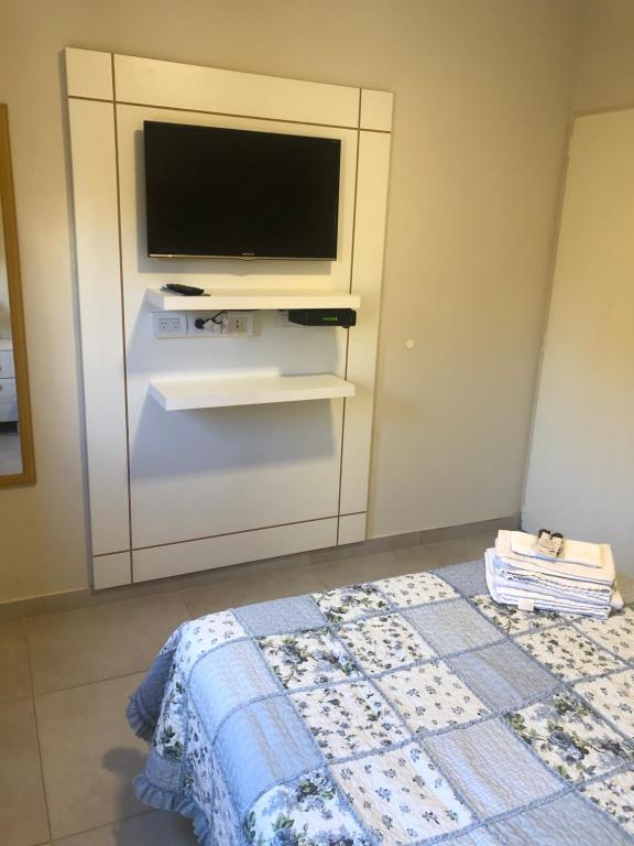 uma sala de estar com uma televisão e uma cama em La Pedrera em Villa María