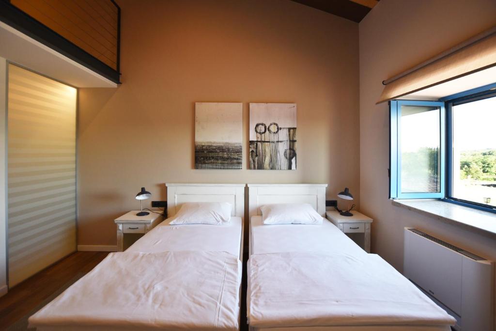two beds in a room with two windows at Bed&Breakfast Monte Rosso in Poreč