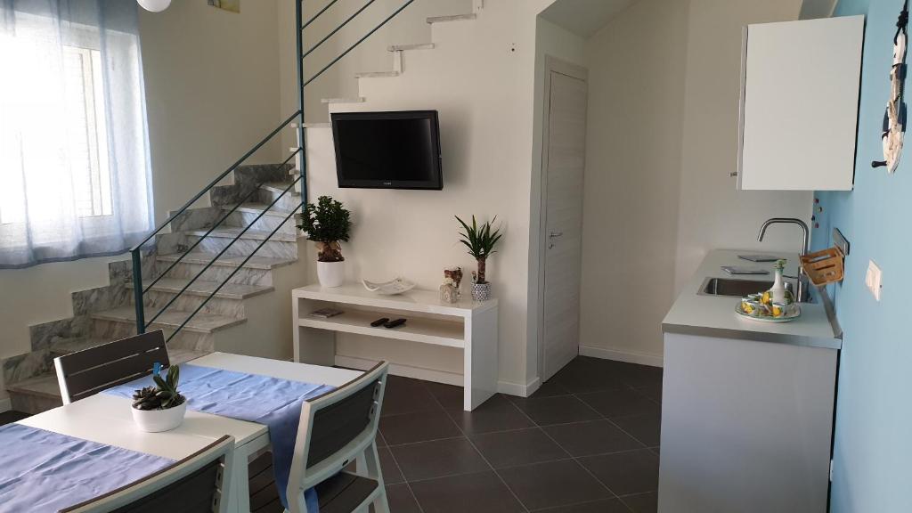 a kitchen and dining room with a table and a television at Marina bay house in Rossano