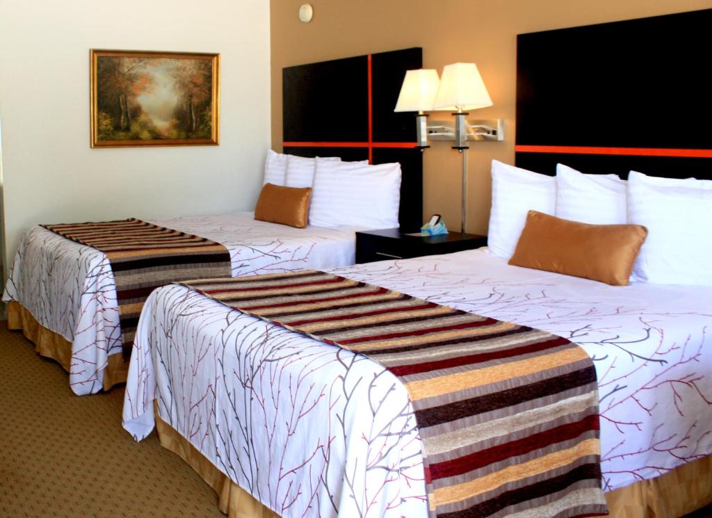 a hotel room with two beds with white sheets at Chaparral Motor Inn in Burlington