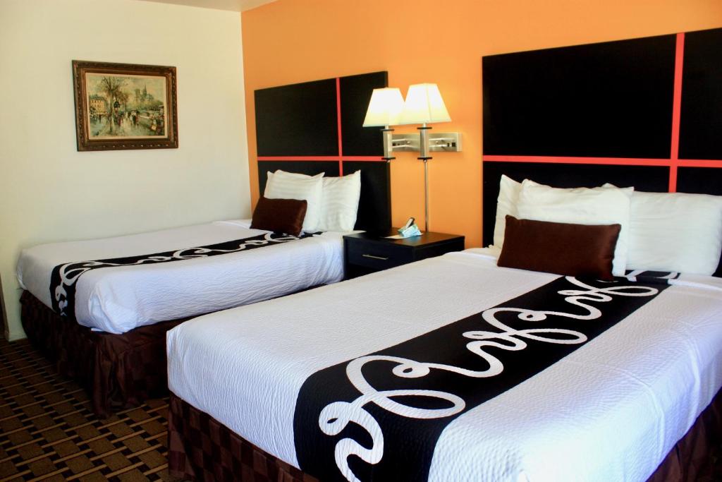 a hotel room with two beds with white sheets at Chaparral Motor Inn in Burlington