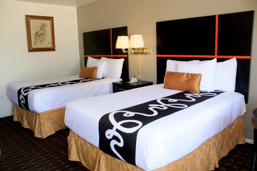 two beds in a hotel room with white and black sheets at Chaparral Motor Inn in Burlington