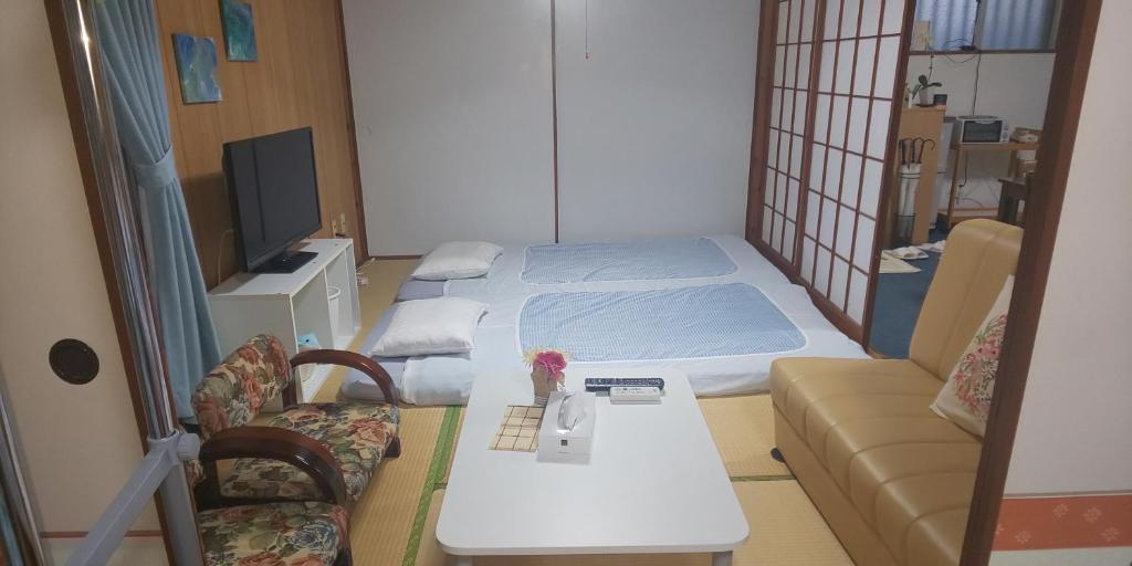 a room with a bed and a table and a couch at Miyagi Apartment Tomari in Naha