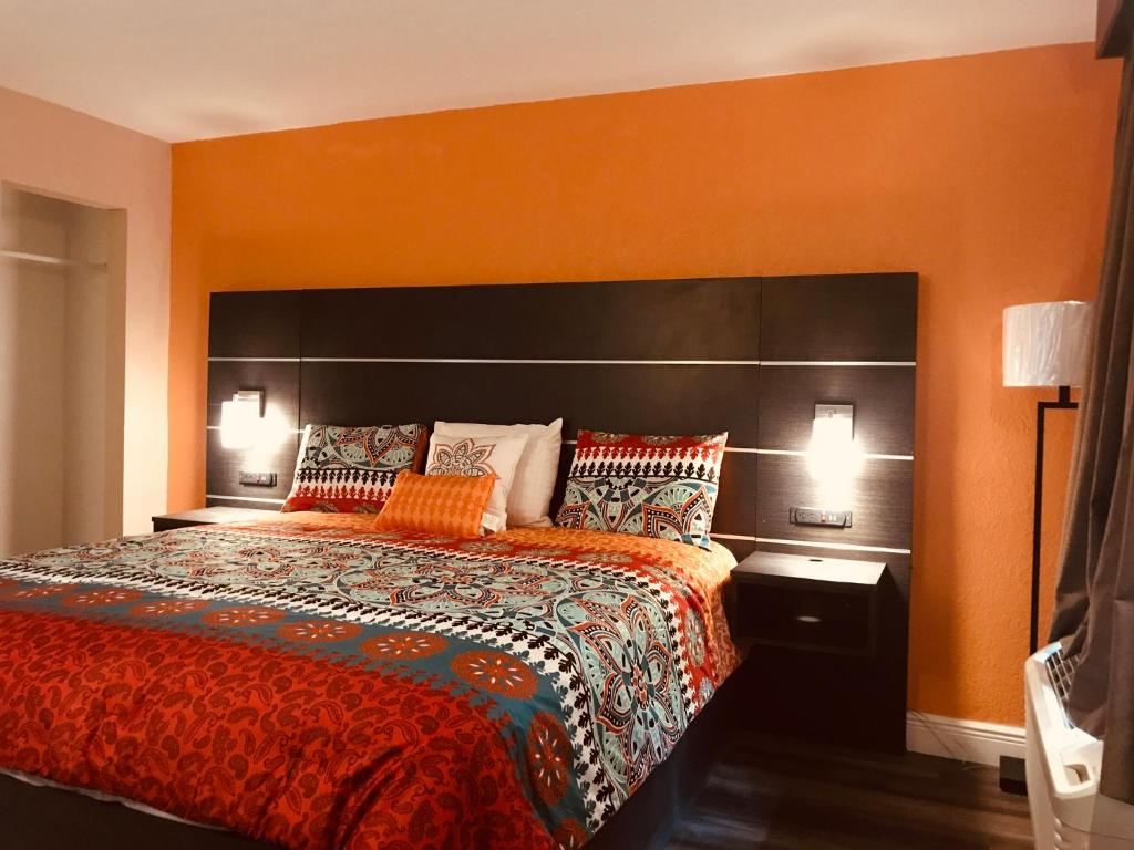 sypialnia z dużym łóżkiem z pomarańczową ścianą w obiekcie Tropical Inn & Suites, downtown clearwater w mieście Clearwater