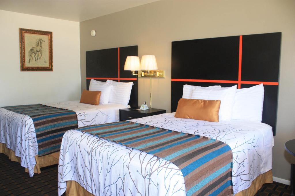a hotel room with two beds with white sheets at Chaparral Motor Inn in Burlington
