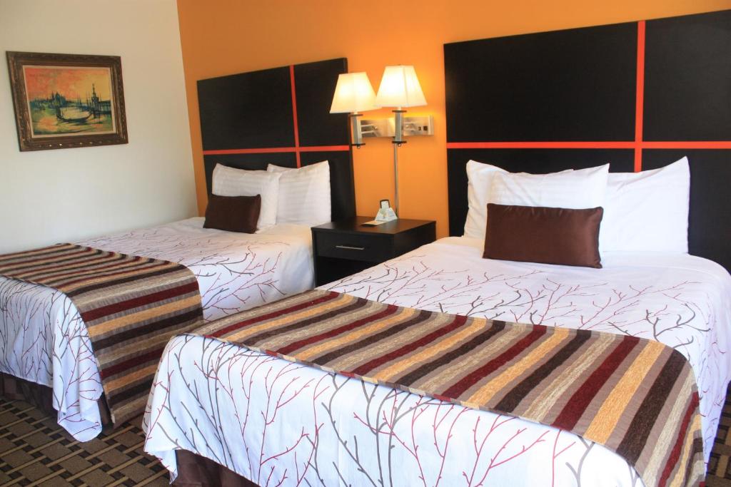 two beds in a hotel room with white and orange walls at Chaparral Motor Inn in Burlington