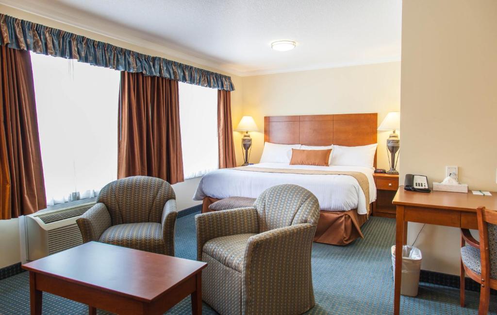 a hotel room with a bed and two chairs at Hinton Lodge in Hinton