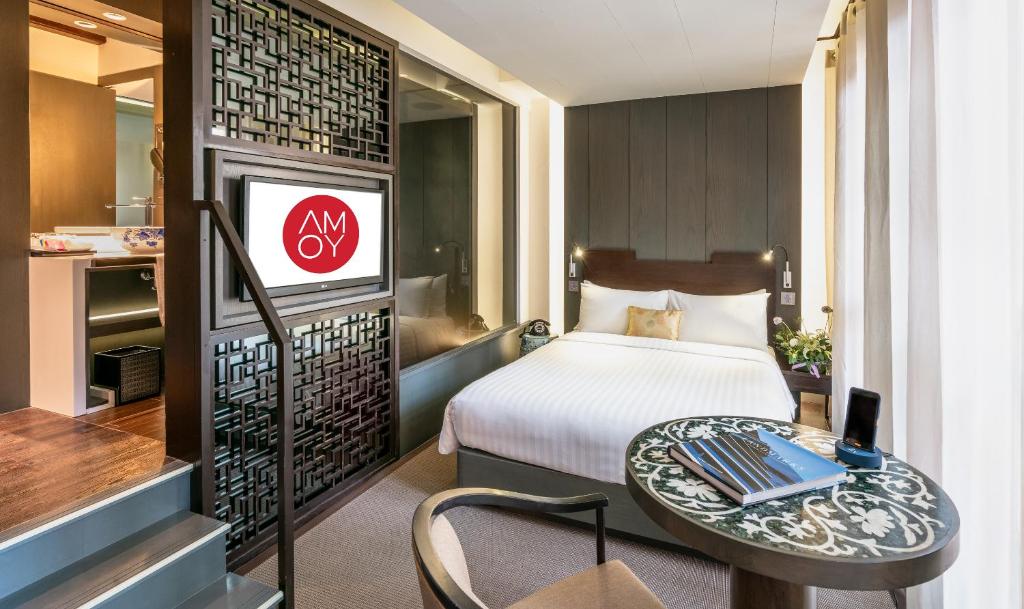 a hotel room with a bed and a table and a television at AMOY by Far East Hospitality in Singapore