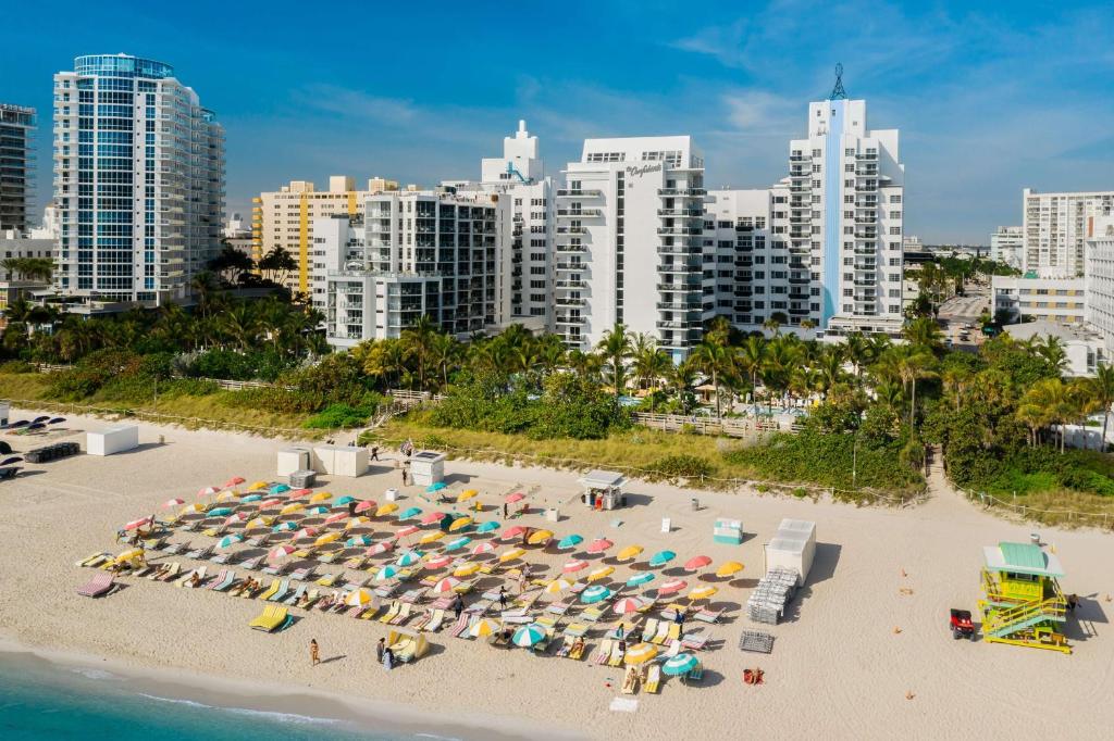 an aerial view of a beach with umbrellas and buildings at The Confidante Miami Beach, part of Hyatt in Miami Beach