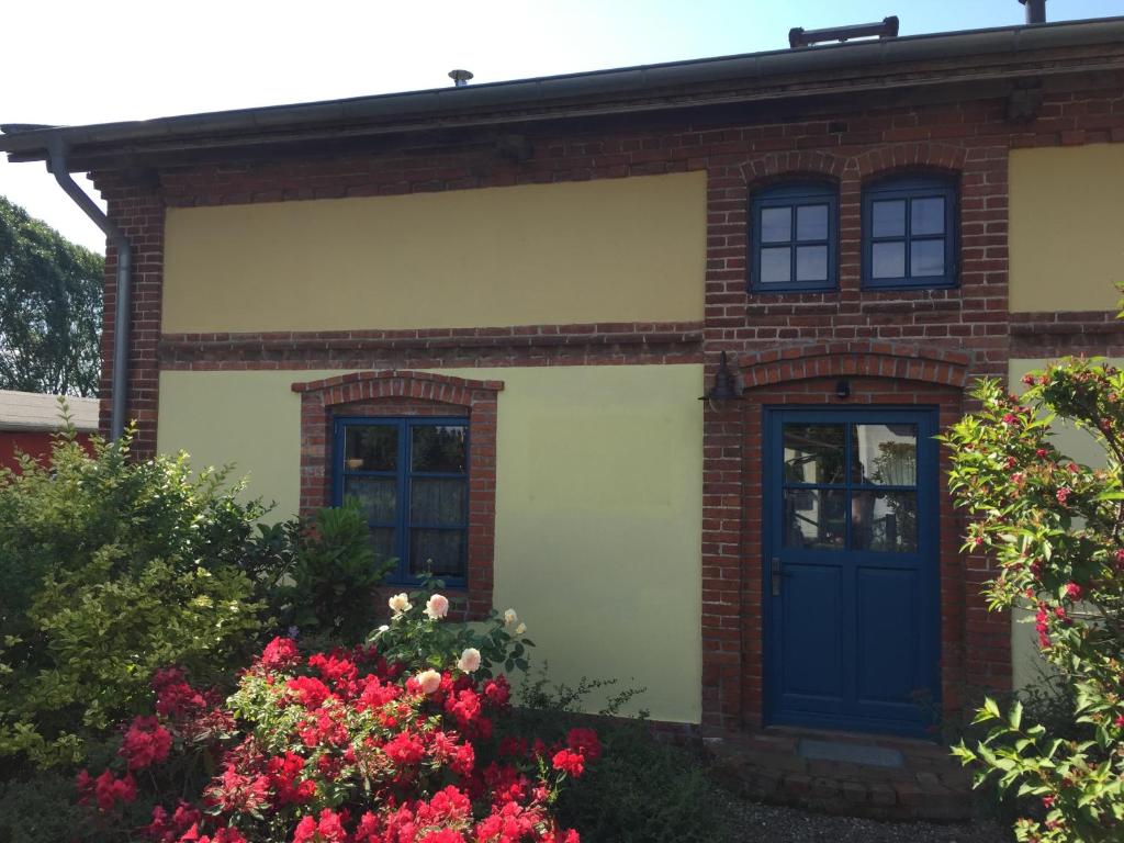 a brick house with a blue door and flowers at Romantische Ferienhaus an der Ostsee mit großem Garten in Rerik