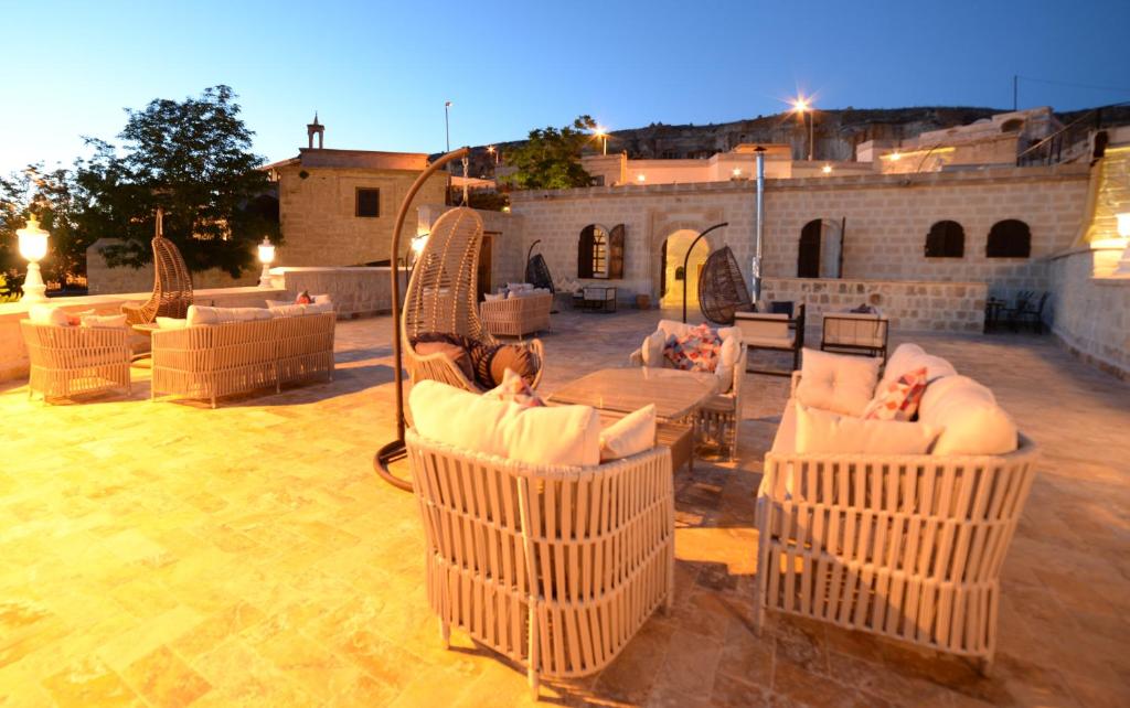 a patio with wicker chairs and tables in front of a building at Crassus Cave Hotel in Urgup