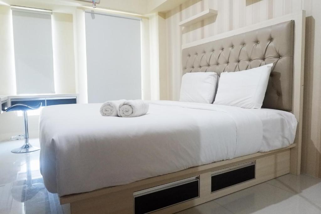 a bedroom with a large white bed with towels on it at Clean Studio Apartment Connected to Mall at Orchard Supermall Mansion By Travelio in Surabaya