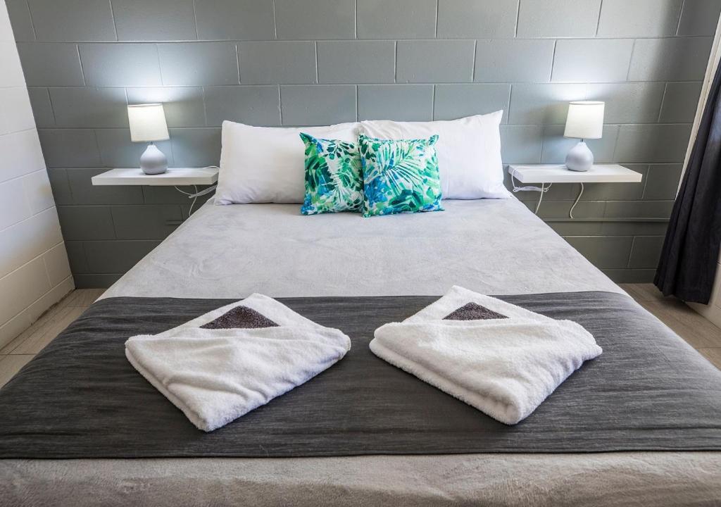 a bed with two white towels on top of it at Banjo Paterson Motor Inn in Townsville