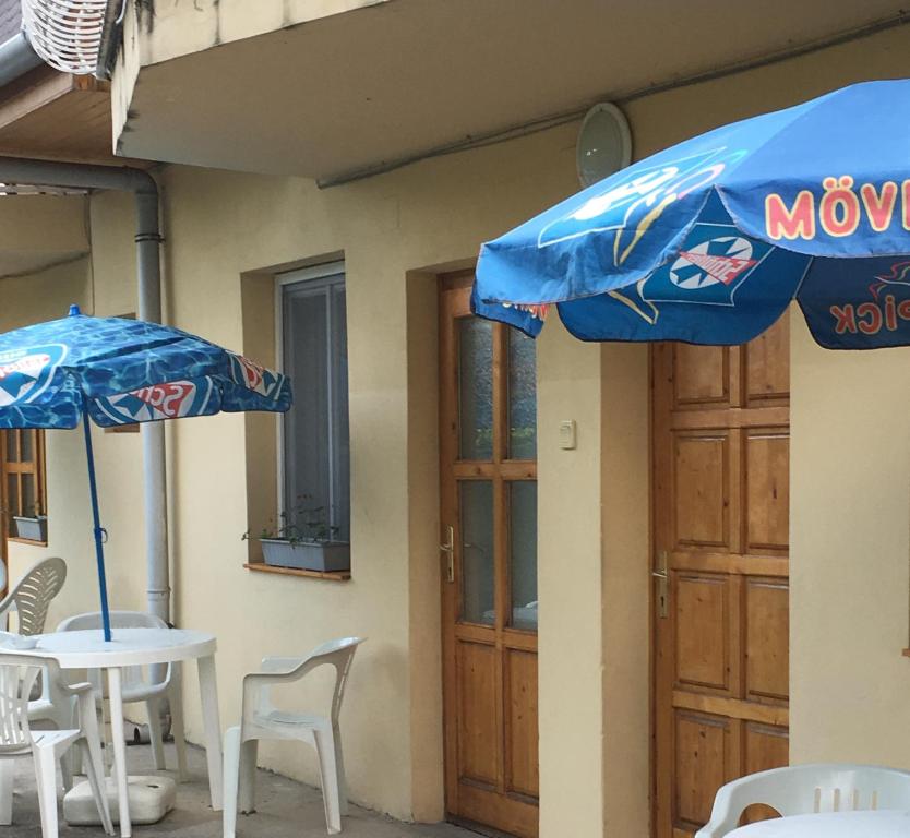 dwa błękitne parasole siedzące obok stołu i krzeseł w obiekcie Fasor vendégház w mieście Balatonszemes
