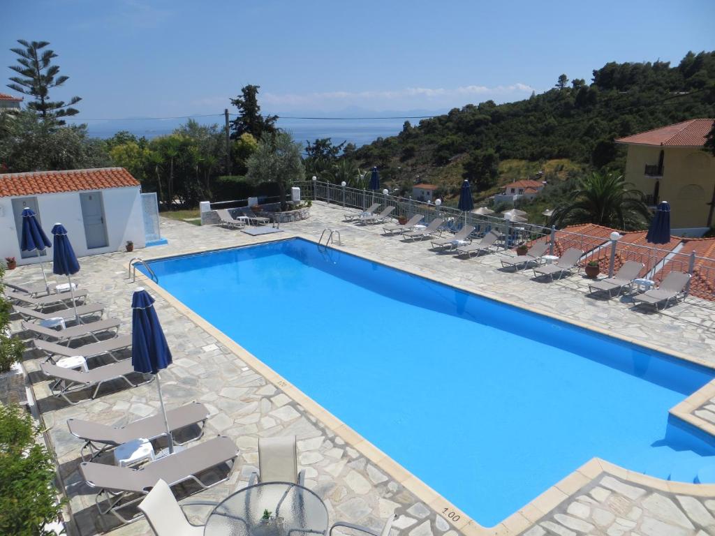 a swimming pool with chaise lounge chairs and a resort at Poseidon in Stafylos