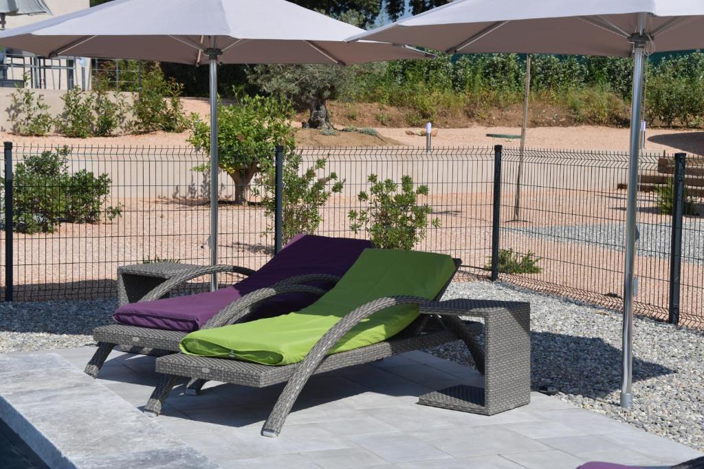 a wicker chair sitting under an umbrella at Sous Les Pins gîtes et chambres d'hôtes in La Londe-les-Maures