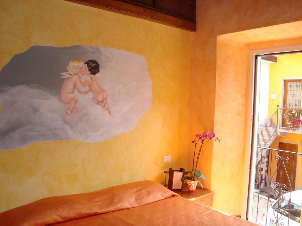 ヴェルバーニアにあるResidenza Pesce D'Oroの壁に描かれた女の子2人の絵画が飾られたベッドルーム