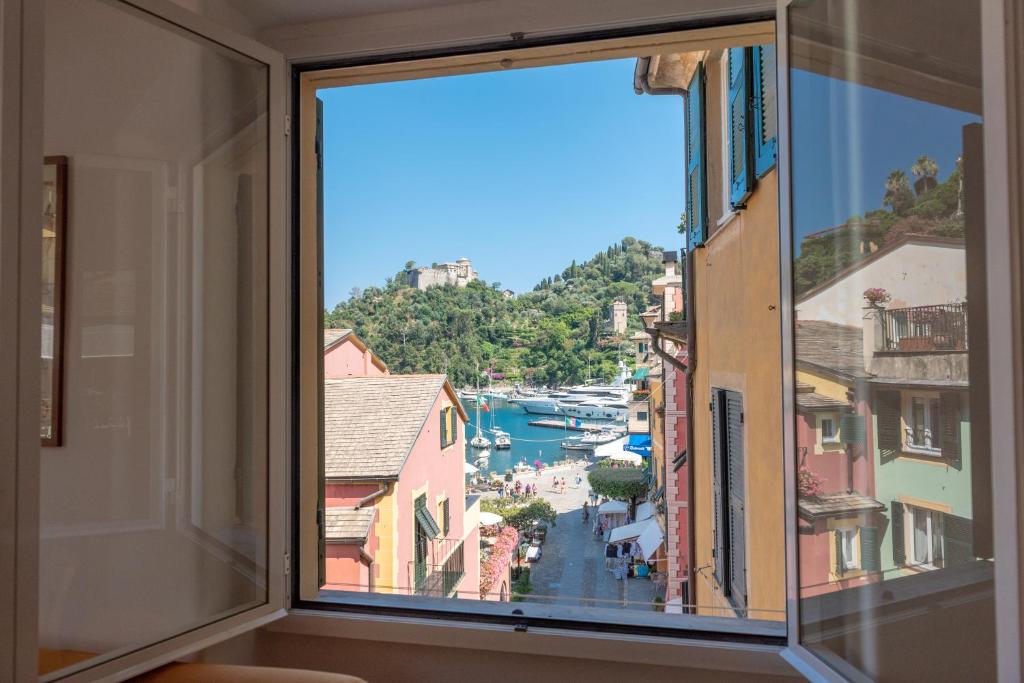 une fenêtre avec vue sur la rivière et les bâtiments dans l'établissement Cocca's House by PortofinoVip, à Portofino