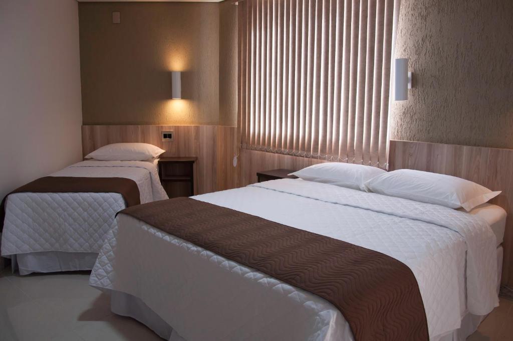 um quarto de hotel com duas camas e uma janela em Hotel Domus Itabira em Itabira