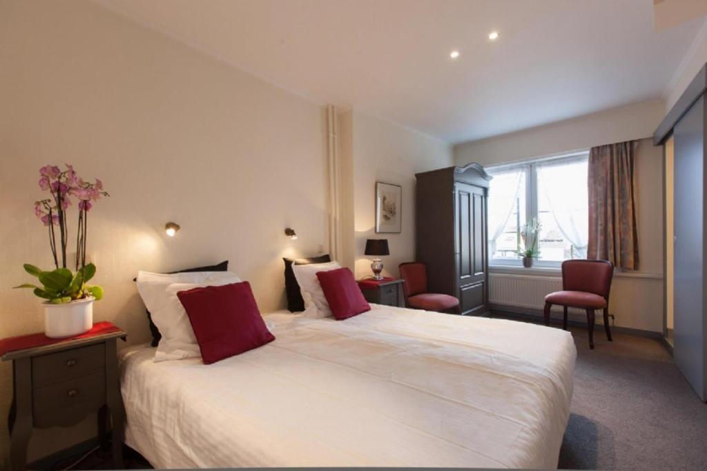een hotelkamer met een groot wit bed met rode kussens bij Gillis Eight by Romy&Travis in Brugge