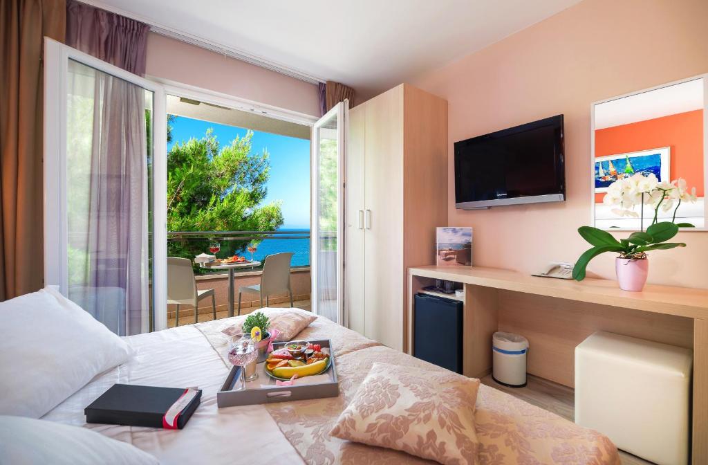 a hotel room with a bed, television and a table at Hotel Maritimo in Makarska