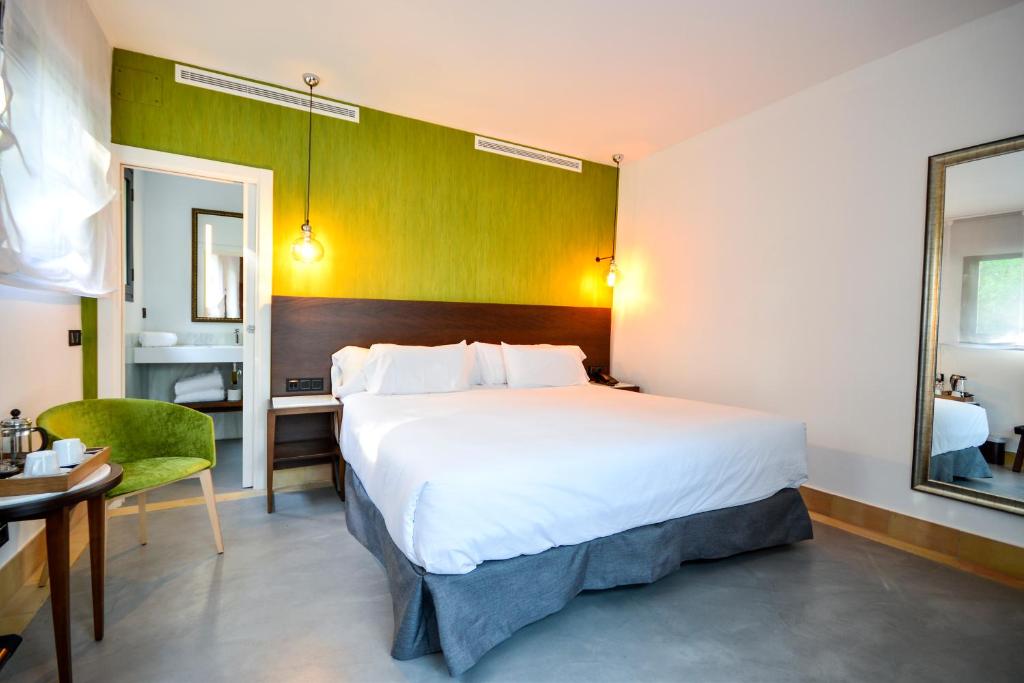 a hotel room with a large bed and a desk at Hotel Legado Alcazar in Seville