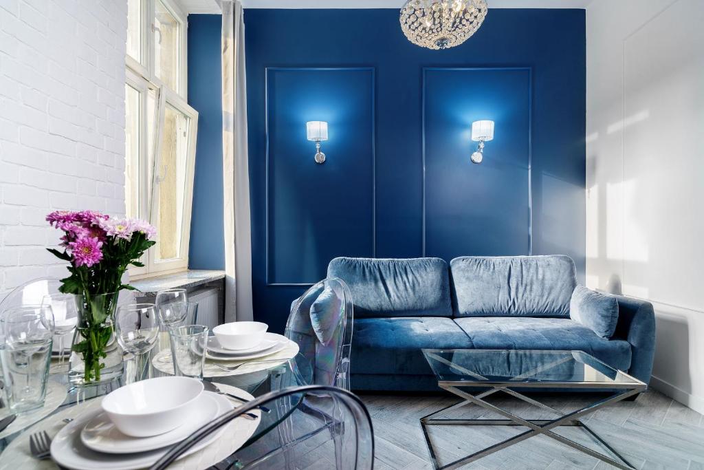 een woonkamer met een blauwe bank en een glazen tafel bij RentPlanet - Apartamenty Szewska in Wrocław