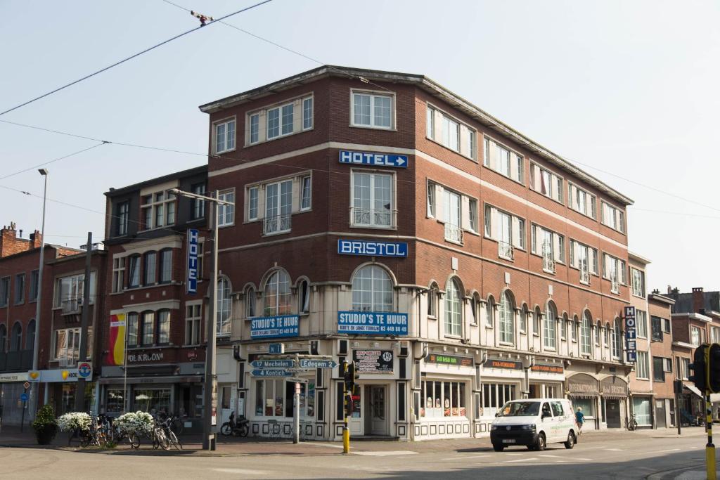 een gebouw op de hoek van een straat met een auto voor de deur bij Hotel Bristol Internationaal in Mortsel