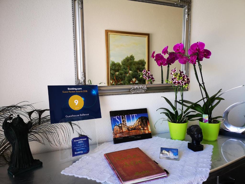 a desk with a book and flowers and a mirror at Villa Bellevue in Vis