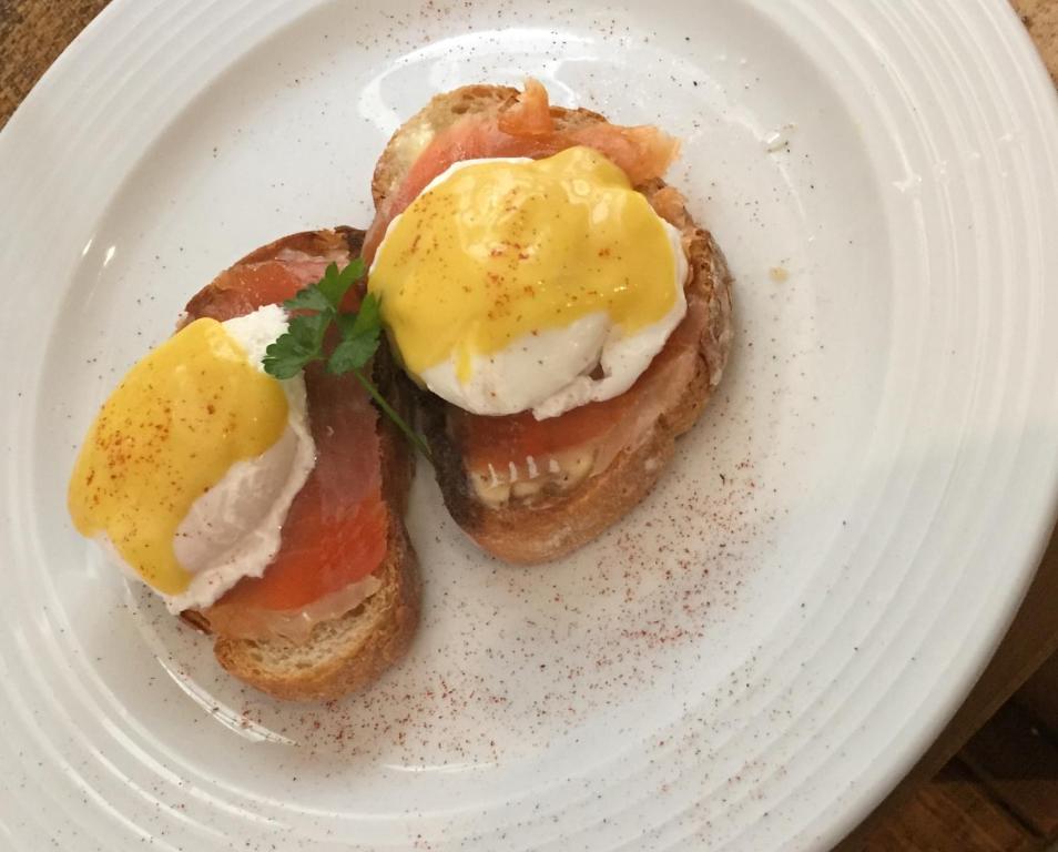 a white plate with two eggs on top of toast at L'Ancienne Boulangerie in Collinée