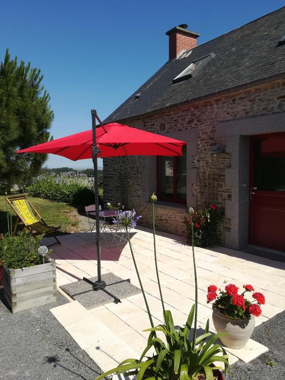 - un parasol rouge sur une terrasse en face d'une maison dans l'établissement Les Agapanthes, à Huisnes-sur-Mer