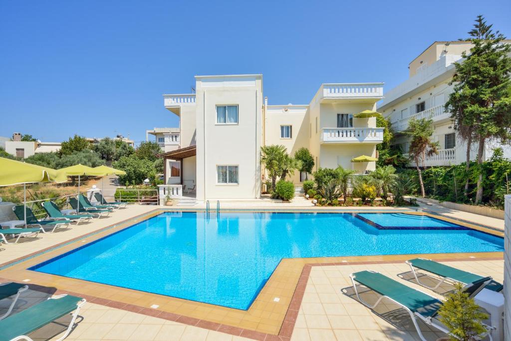 a swimming pool in front of a building at Poseidon Apartments in Kato Daratso