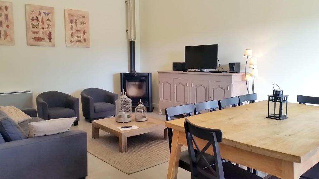 - un salon avec une table, des chaises et une télévision dans l'établissement Gites Domaine de Ceyrac, à Conqueyrac