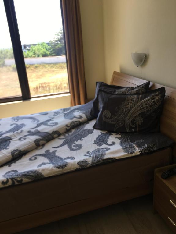 a bed with a blue and white blanket and a window at Aparthotel Afrodita 2 in Sinemorets