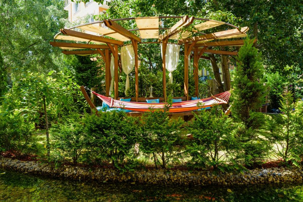 a wooden carousel in a garden with trees at Sweet Homes Apartments in Sunny Beach