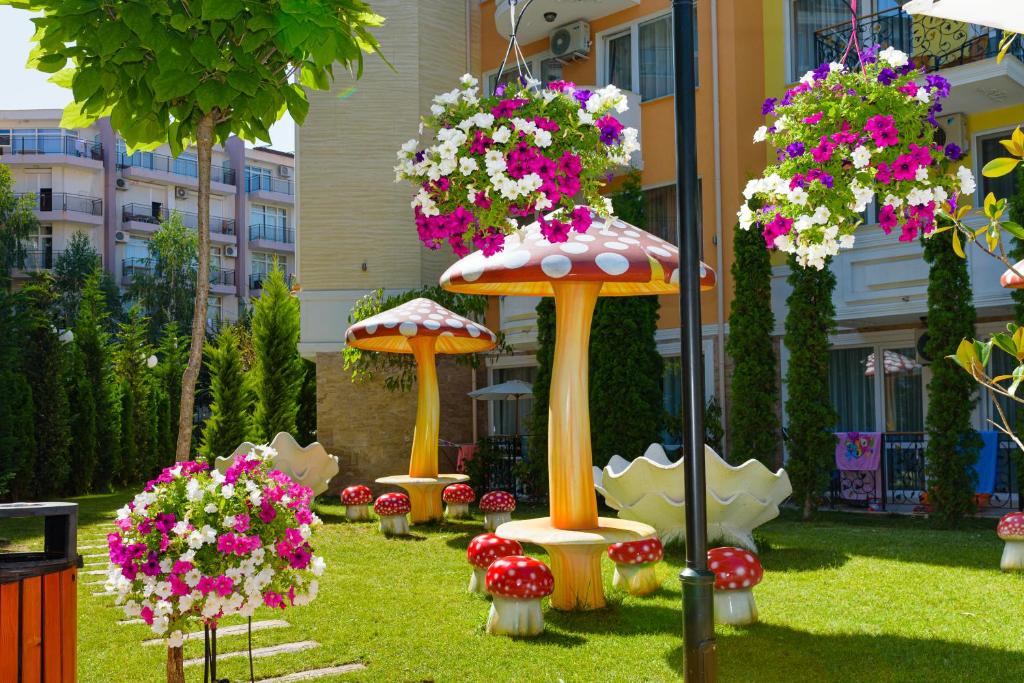 a garden with umbrellas and flowers in the grass at Sweet Homes Apartments in Sunny Beach