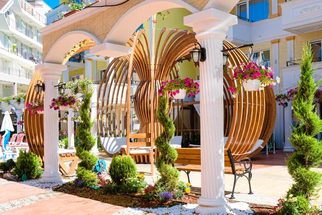 a patio with chairs and a bench and flowers at Sweet Homes Apartments in Sunny Beach