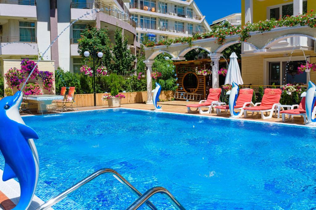 a large swimming pool with chairs and a building at Sweet Homes Apartments in Sunny Beach