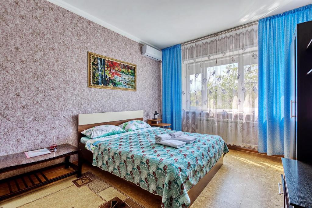 a bedroom with a bed and a window with blue curtains at Apartment near the President's Park. Orbita-2 in Almaty
