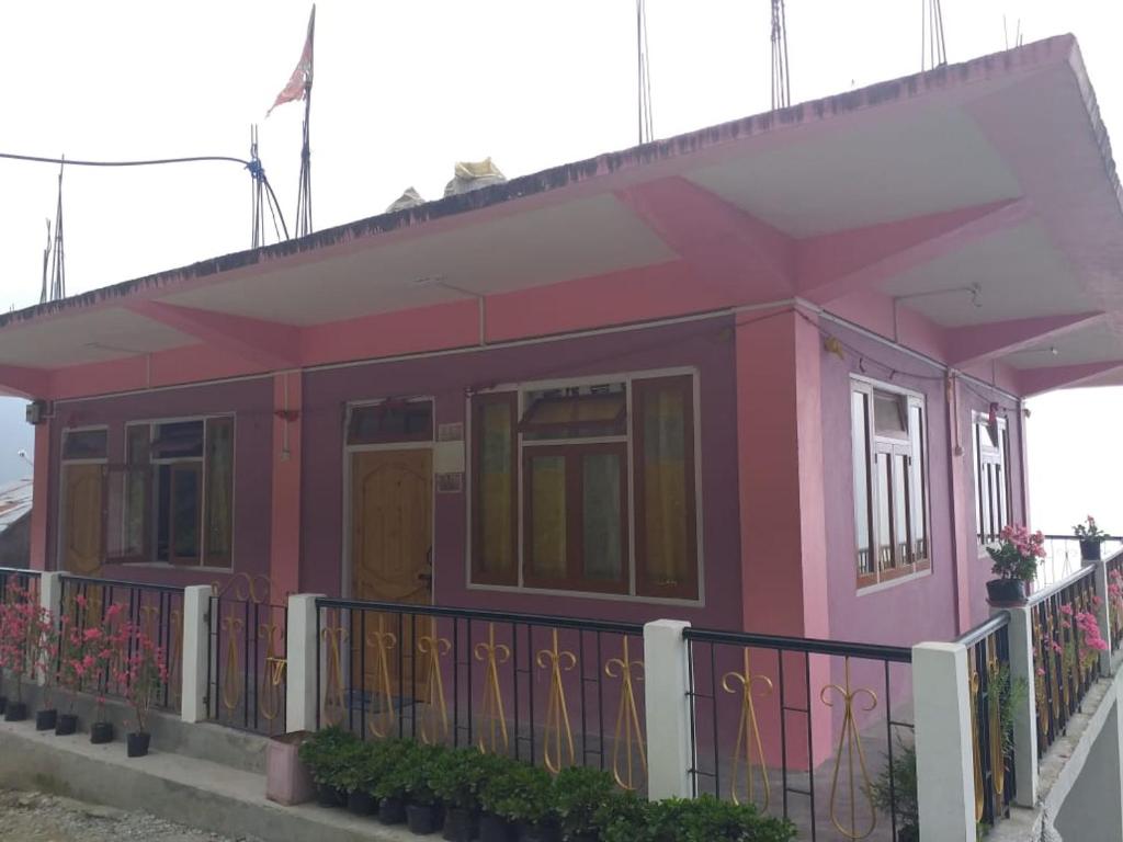 a small pink house with a fence at Vamoose Ashis Homestay in Pedong