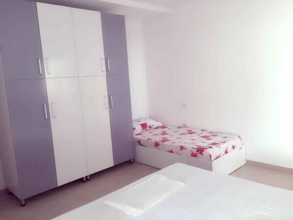 a white bedroom with a bed and a cabinet at Eriola apartament in Orikum
