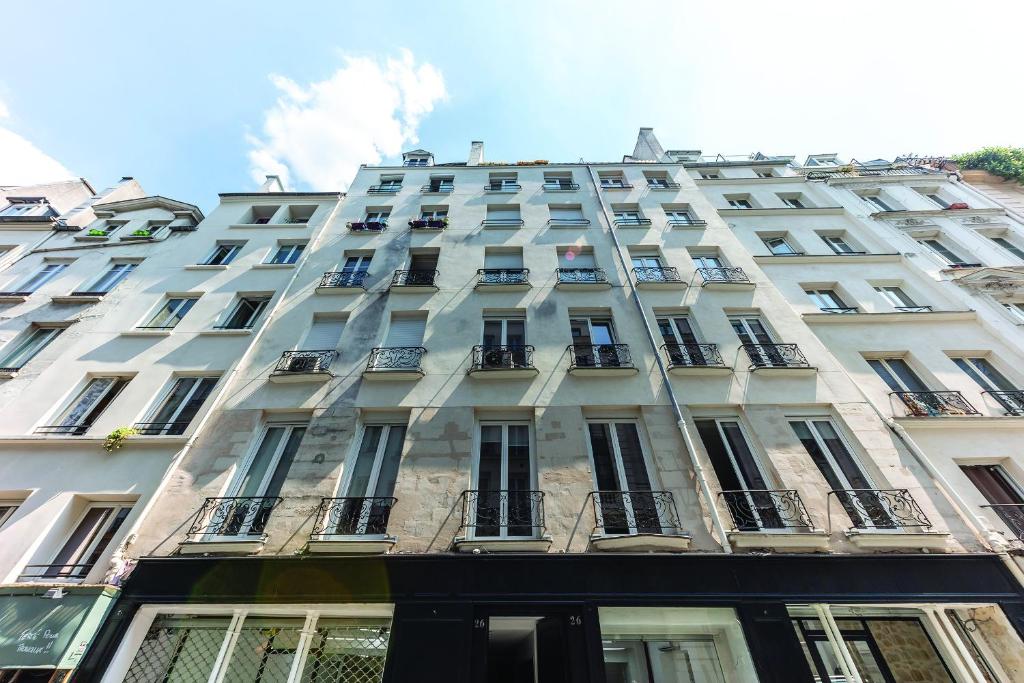 a tall white building with windows and balconies at Maison le Bac Apartments in Paris