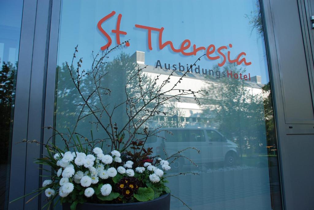 una ventana de una tienda con un jarrón de flores en Ausbildungshotel St. Theresia en Múnich