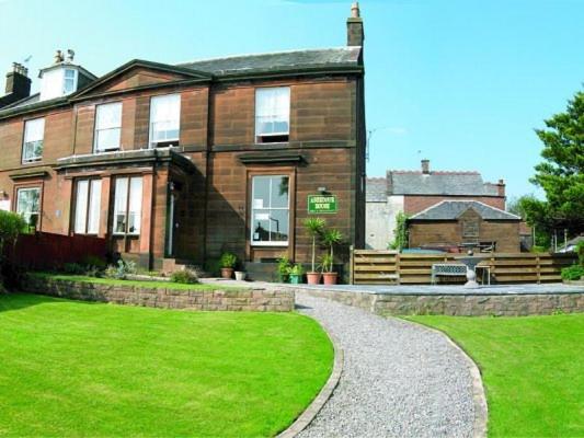 una gran casa de ladrillo con un césped verde delante de ella en Dumfries Villa, en Dumfries