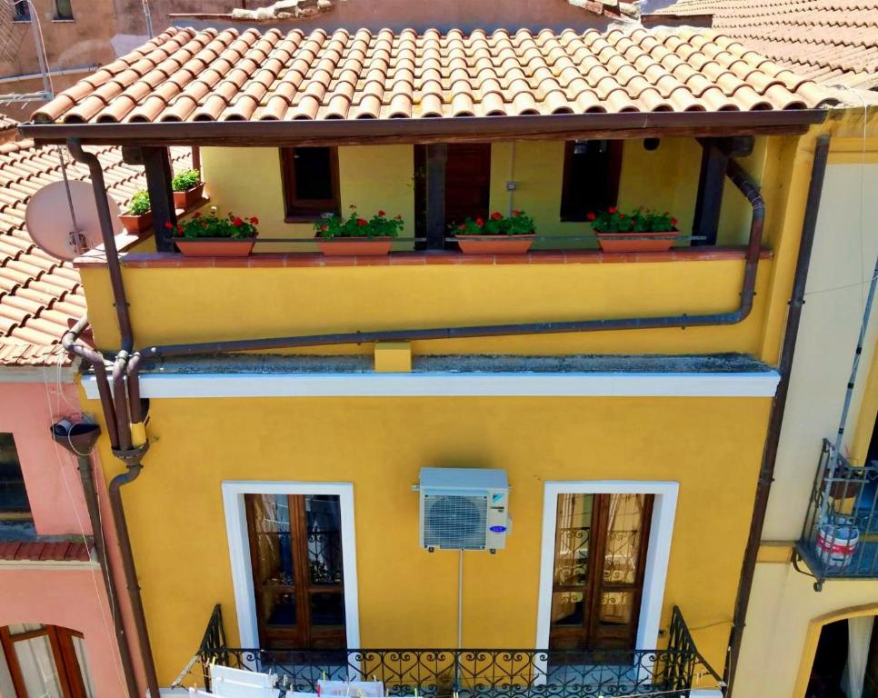 uma casa amarela com vasos de plantas numa varanda em Il Terrazzino Iglesias em Iglesias
