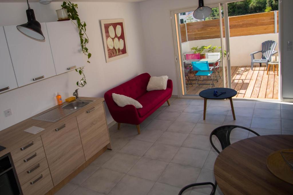 uma cozinha com um sofá vermelho e uma mesa em Les Terrasses de Bella Vista - Belle maison bord de mer em Saint-Vincent-sur-Jard