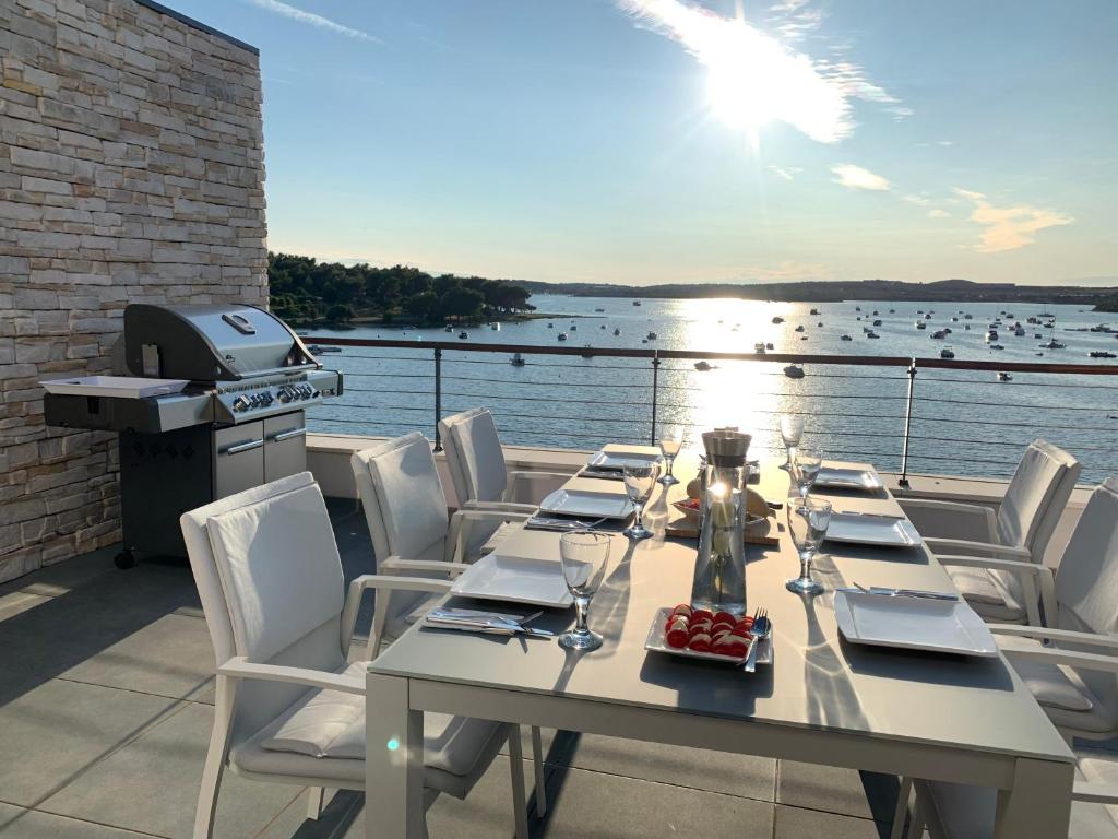 einen Tisch mit weißen Stühlen und einen Grill auf dem Balkon in der Unterkunft SEAVIEW in Medulin