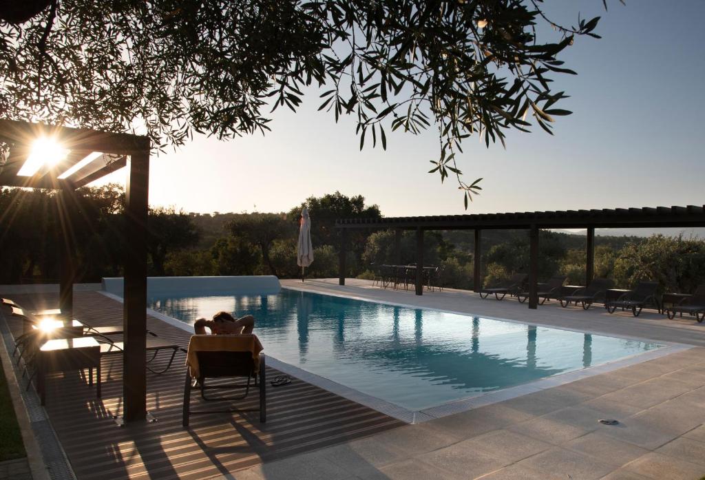 ein Pool mit einer Person, die in einem Stuhl daneben sitzt in der Unterkunft Casas do Regato in Castelo Branco