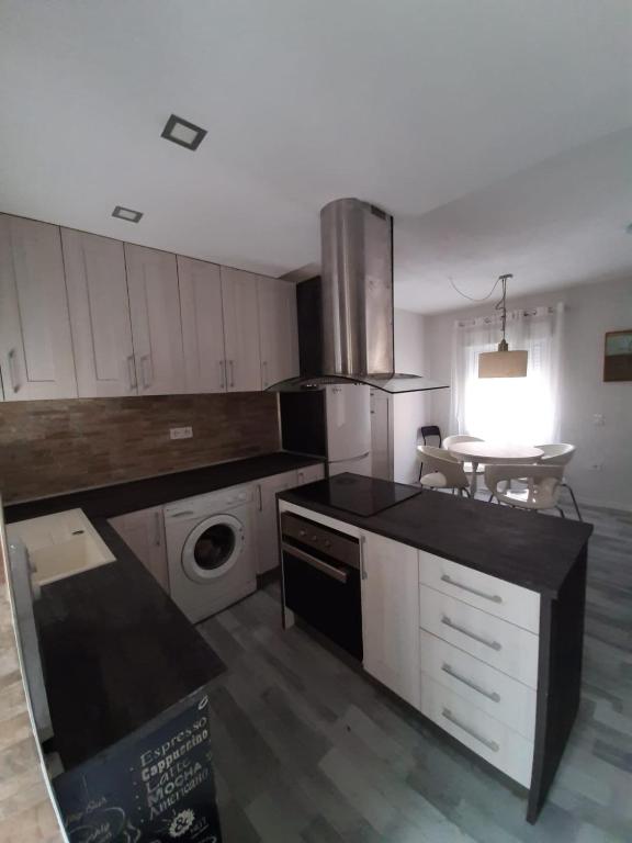a kitchen with white cabinets and a washer and dryer at Casa aragon in Boadilla del Monte