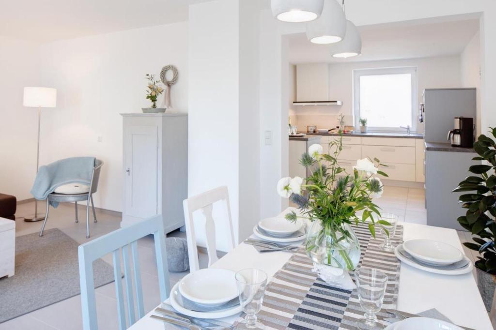 a white dining room with a table with plates and flowers at Ferienwohnung Am Stadtpark in Schwäbisch Hall